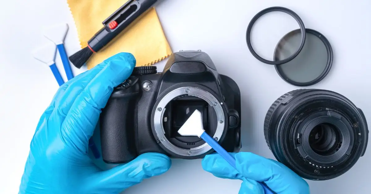 Técnico realizando manutenção preventiva de câmeras e lentes com luvas de proteção